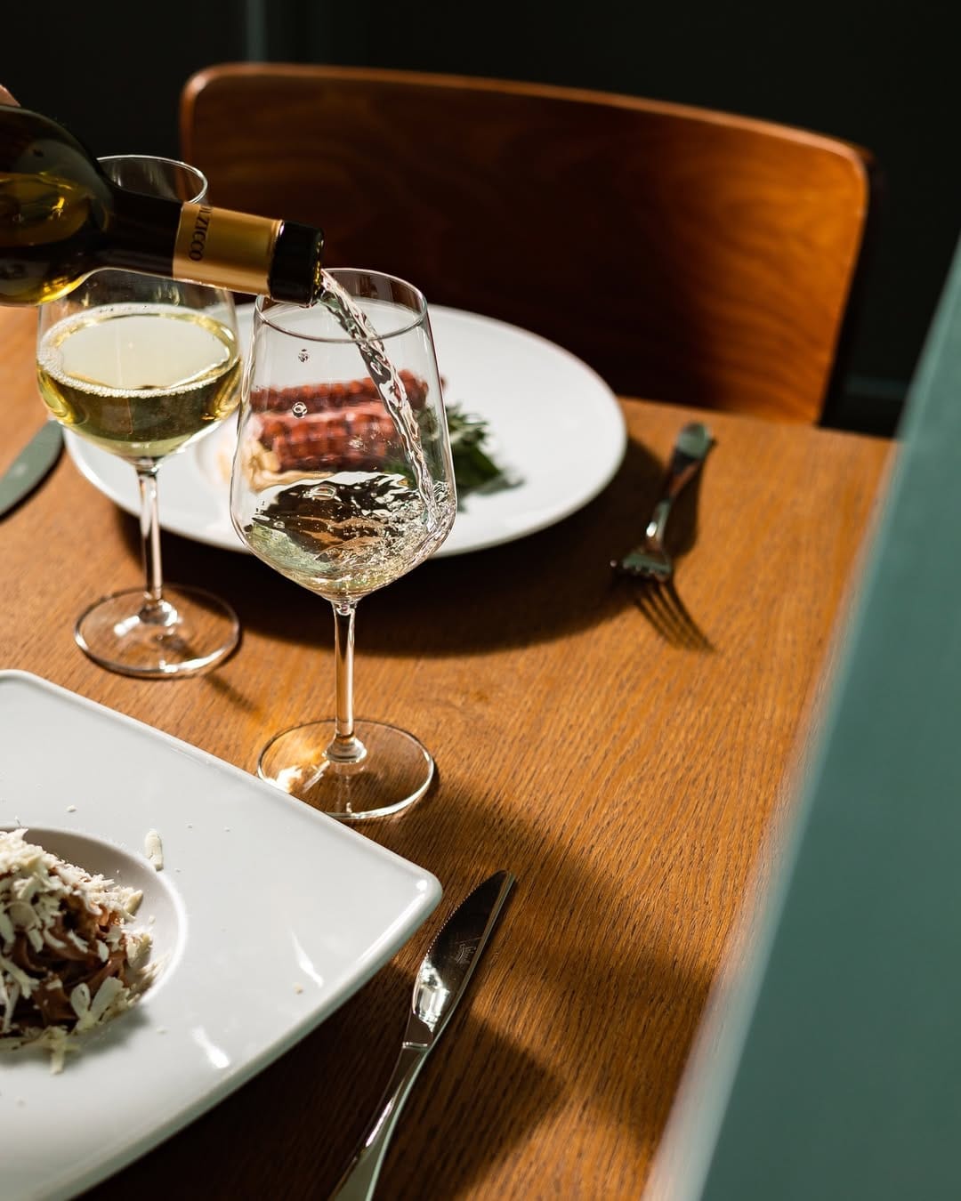 Calice di vino bianco versato a tavola durante una cena da Catarina Bistrot