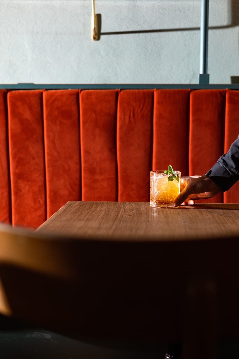 Cocktail artigianale al tavolo – Catarina Bistrot Torino Cocktail artigianale servito al tavolo nel bistrot Catarina a Torino, con sedute rosse e atmosfera intima