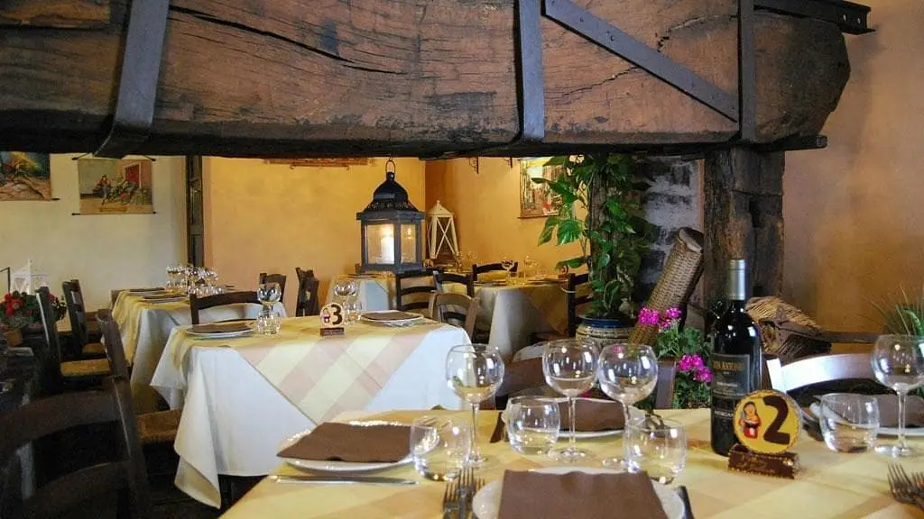 L'Interno elegante dell’Osteria del Siciliano a Nicolosi che mostra i tavoli apparecchiati, perfetto per cene romantiche e pranzi in famiglia.