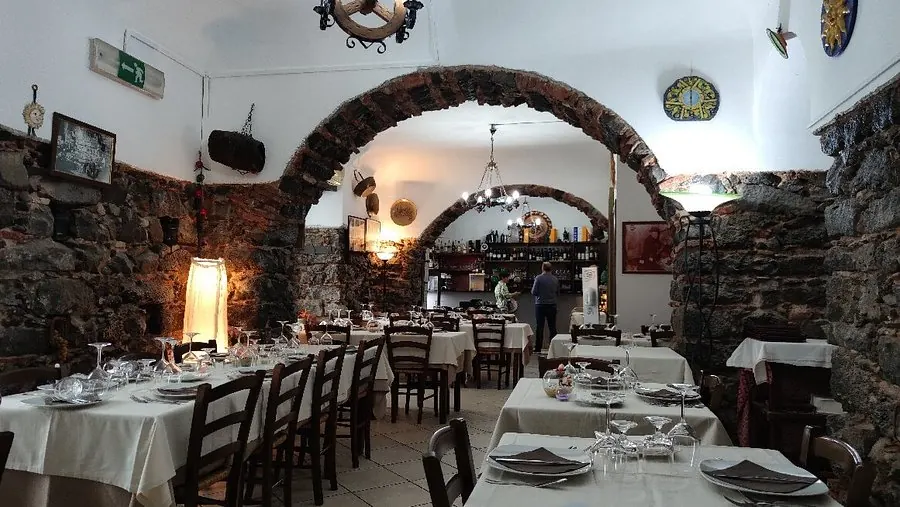 Sala del ristorante Sicilia in Bocca con archi in pietra lavica e tavoli apparecchiati, Catania
