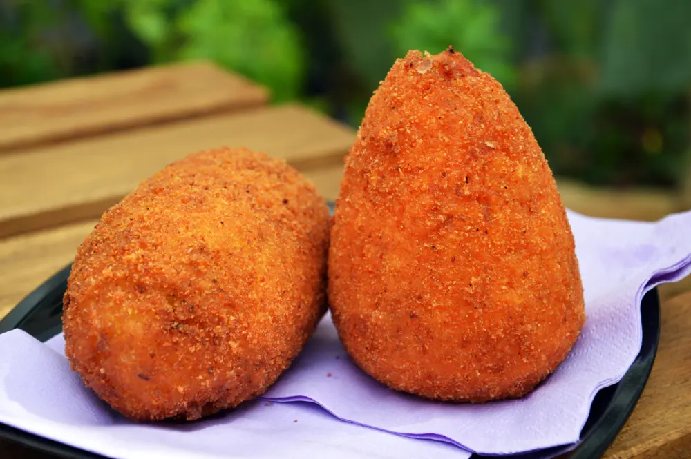 Arancino siciliano dorato e croccante, ripieno di riso, ragù, piselli e formaggio filante – street food tipico della Sicilia. Arancino siciliano dorato e croccante, ripieno di riso, ragù, piselli e formaggio filante – street food tipico della Sicilia.