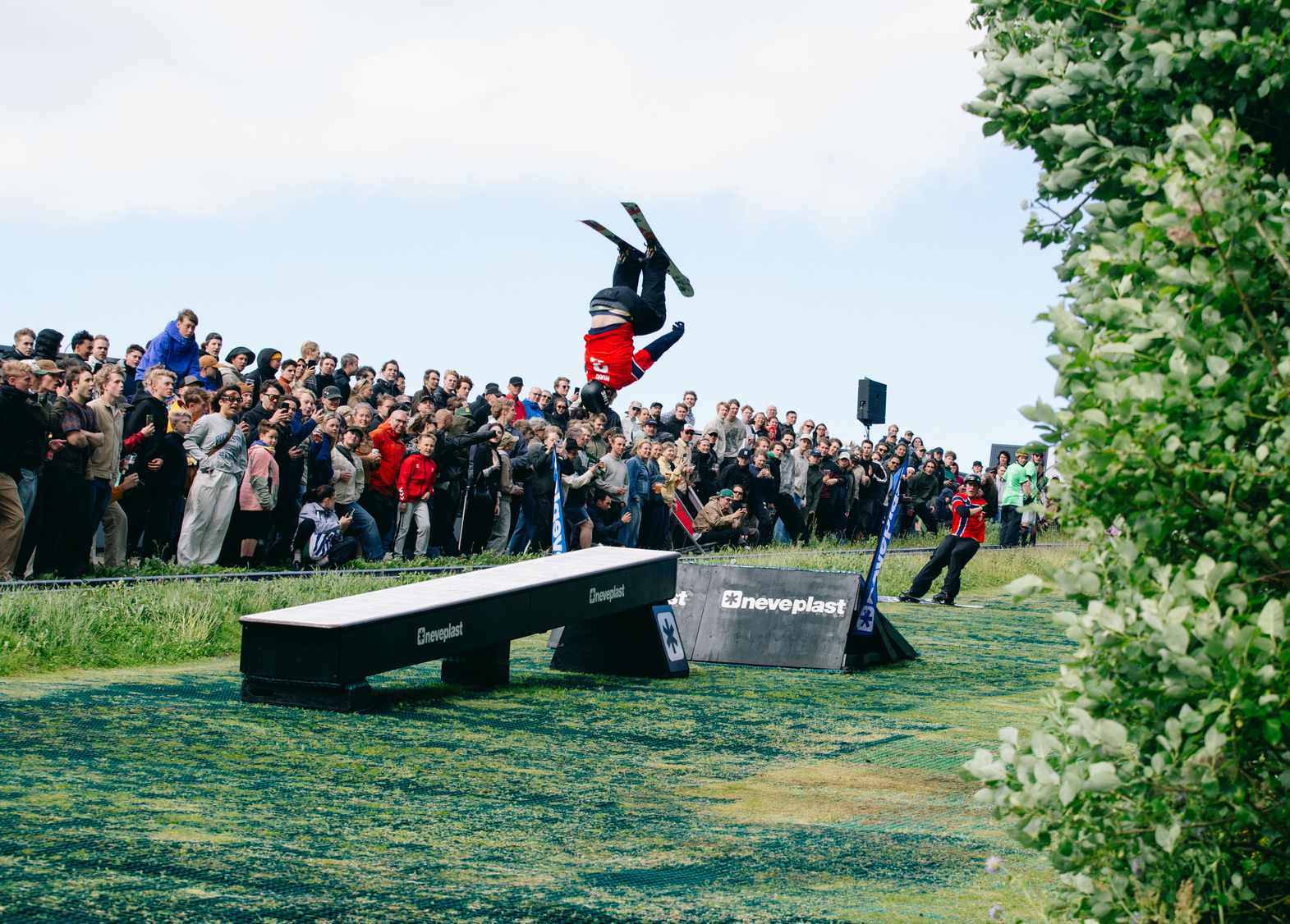 Skier flipping over a Neveplast box in front of a crowd on a synthetic snowpark Skier flipping over a Neveplast box in front of a crowd on a synthetic snowpark
