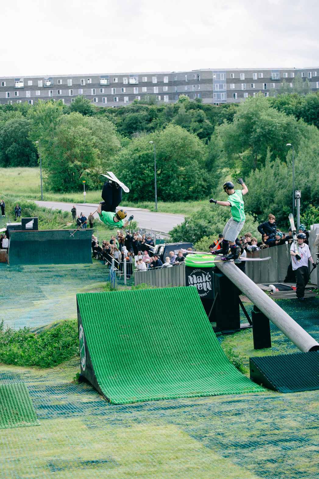 Two skiers riding a kicker and a rail on the Neveplast FreeStyle snowpark surface