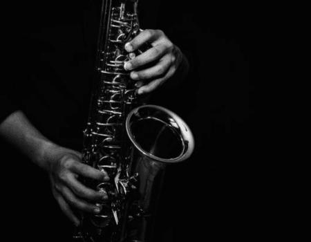 Corsi di sassofono da Valentino Studio Mani che suonano un sax con uno sfondo nero