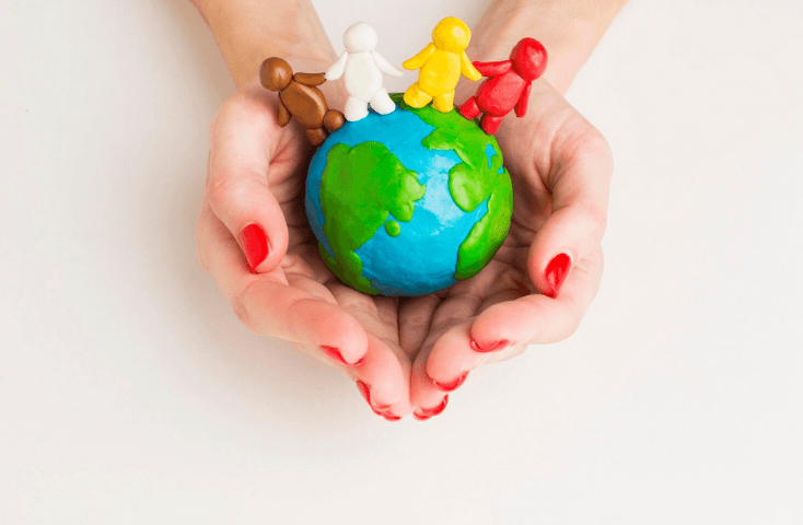 Mani di donna con smalto rosso, che che tengono globo con figurine di persone, pomgo colorato, mondo; bilinguismo infantile, Asilo nodo bilingue: si o no?