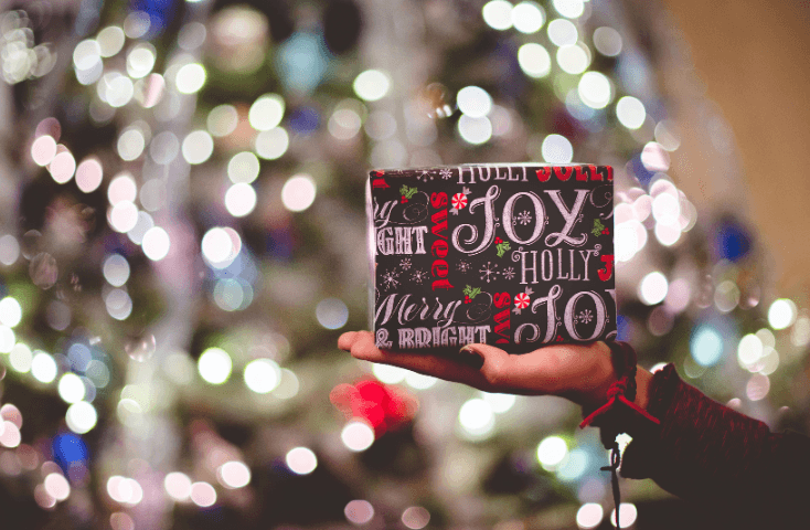 Luci di Natale e abete sullo sfondo, pacco regalo; joy; merry christmas; Poesie di Natale in inglese tradotte in italiano