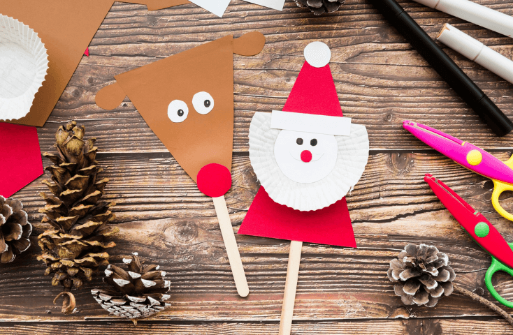renna e babbo natale di carta; pigna; forbice, pennarelli e cartoncini colorati; scrivania in legno vista dall'alto; lavoretti di natale per bambini in inglese