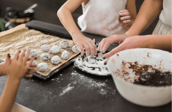 Bimbi in cucina che preparano con la mamma praline al cioccolato, messe sulla leccarda prima di infornare, teglia, farina, quattro ricette dolci da preparare con i bambini