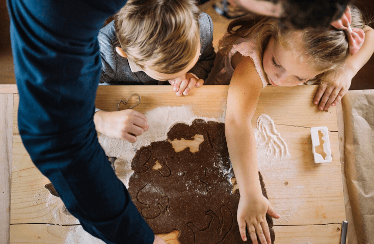 Famiglia che prepara insieme biscotti al cioccolato o pan di zenzero, bambina bionda, bimbo castano con papà, vista dall'alto, quattro ricette dolci da preparare con i bambini