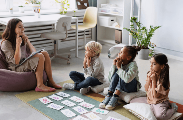 giovane donna che insegna a bambini di diversa etnia la pronuncia di parole, seduta di logopedia con bambino e bambine, 10 errori più comuni degli italiani in inglese