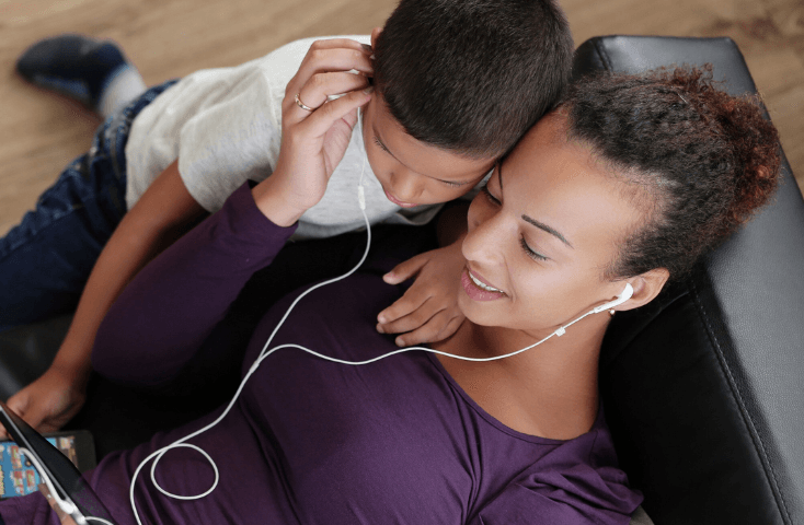 Mamma con il figlio felici a casa ascoltano con gli auricolari e guardano una favola in inglese su youtube, 10 favole in inglese su youtube