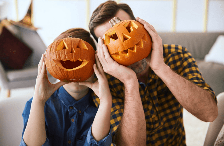 Padre e bambino giocano con delle zucche intagliate, parole importanti in inglese per la festa di halloween
