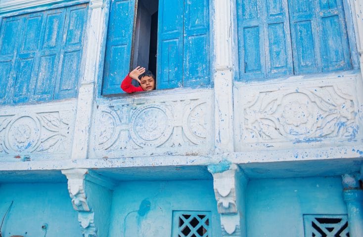bambino affacciato alla balconata di una casa azzurra, come si dice azzurro in inglese