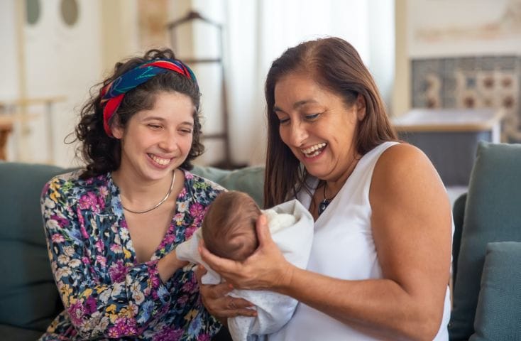 Neomamma che mostra il suo neonato a un'amica sorridendo, come si dice bambino in inglese