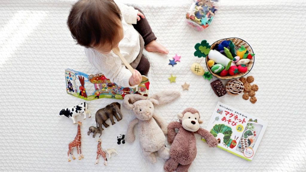 Bambino seduto per terra circondato da giocattoli, nomi dei giocattoli in inglese