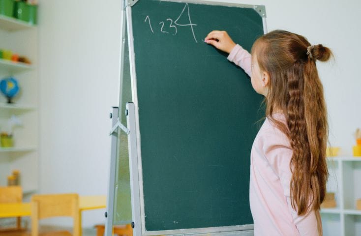 bambina che scrive i numeri alla lavagna, canzoncine per imparare i numeri i inglese
