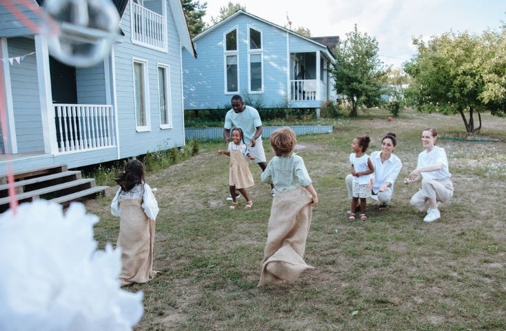 gruppo di bambini che gioca alla corse dei sacchi nel giardino di casa,come si dice casa in inglese