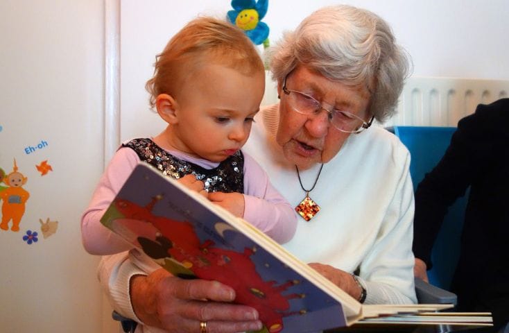 Nonna con in braccio il nipotino e sfogliano un libro insieme, come si dice nonna in inglese