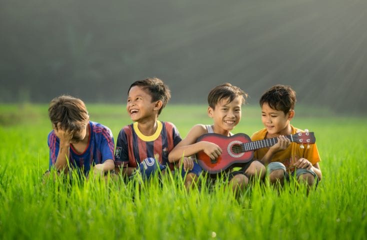 bambini in mezzo a un prato che cantano insieme, come si dice amico in inglese