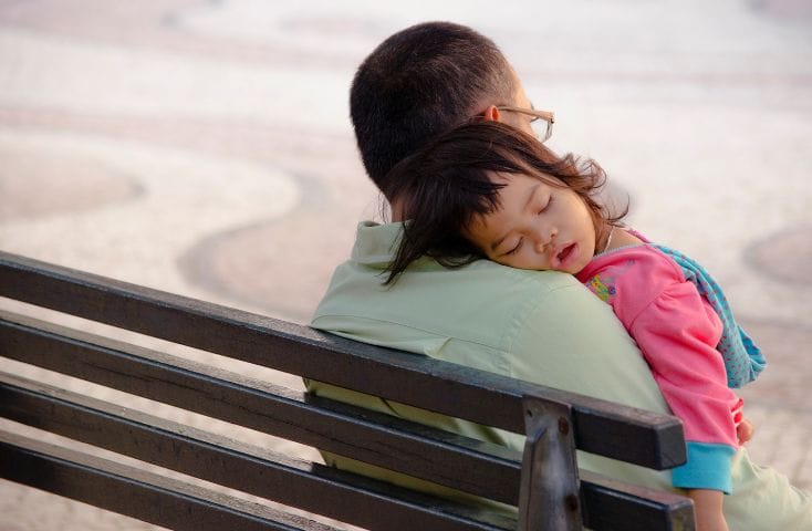 Bimba che dorme sulla spalla del papà seduto su una panchina, 5 modi per dire a un bambino in inglese di andare a letto