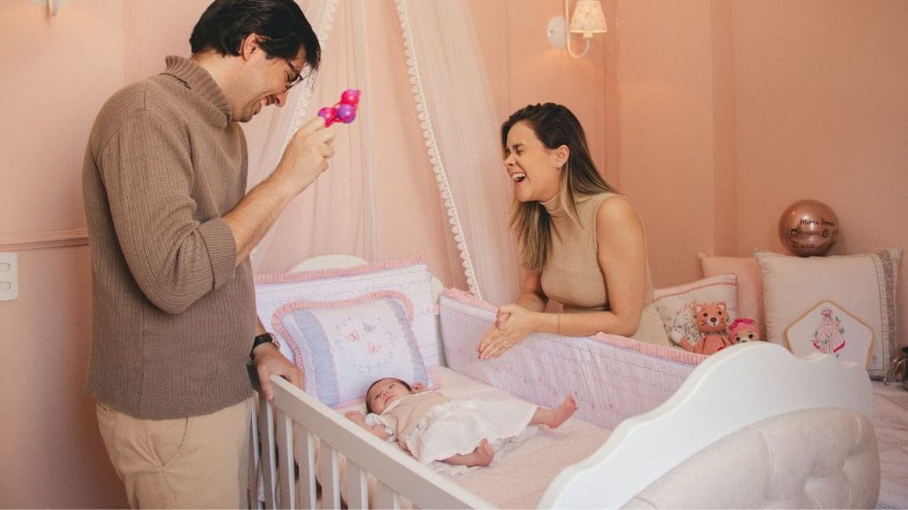Mamma e papà che ridono ai bordi del lettino del bebé, come si dice cameretta in inglese