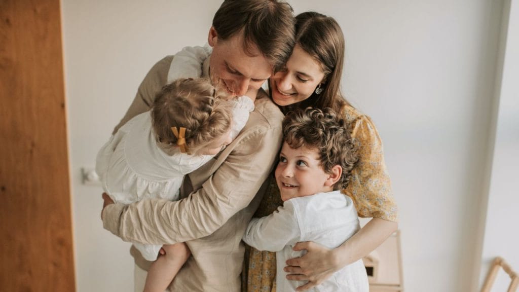 Mamma papà e due bambini che si abbracciano, come si dice ti voglio bene in inglese