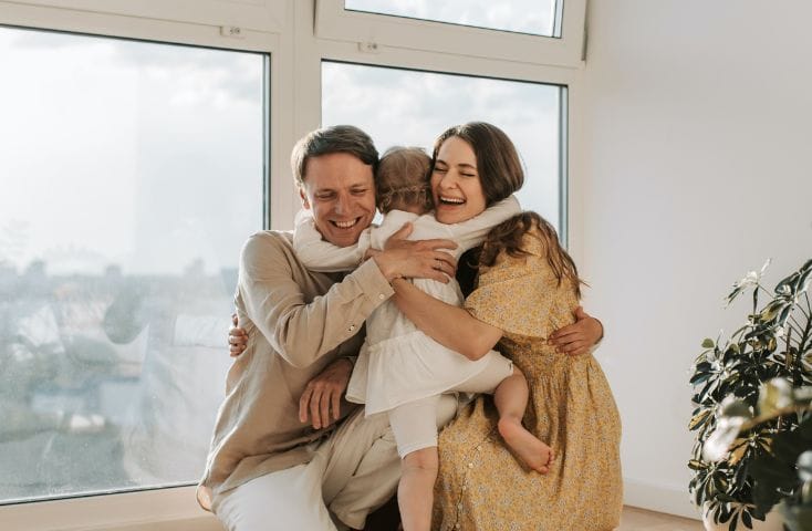 mamma e papà che abbracciano la figlia piccola, come si dice ti voglio bene in inglese