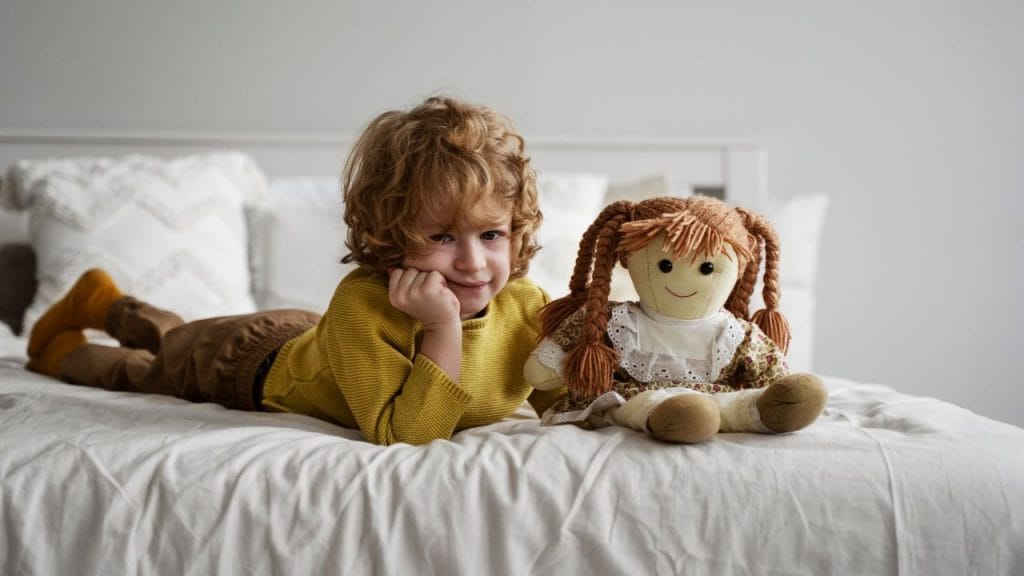 bimbo o bimba sul letto con una bambola, come si dice bambola in inglese