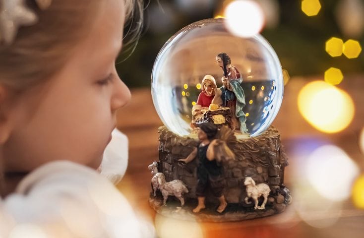 bambina che guarda il presepe in una palla di vetro, come si dice presepe in inglese