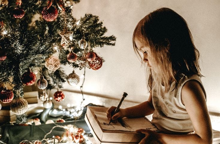 Bmbina che disegna davanti all'albero di Natale