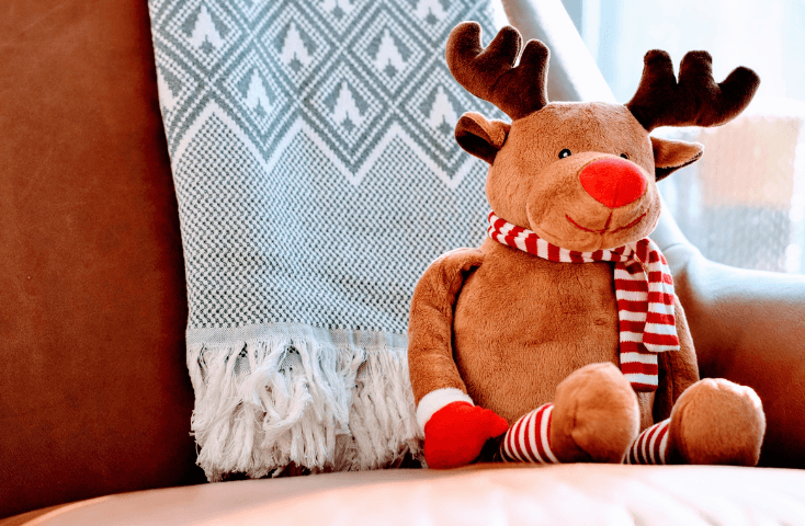 peluche di una renna dal naso rosso seduto su un divano