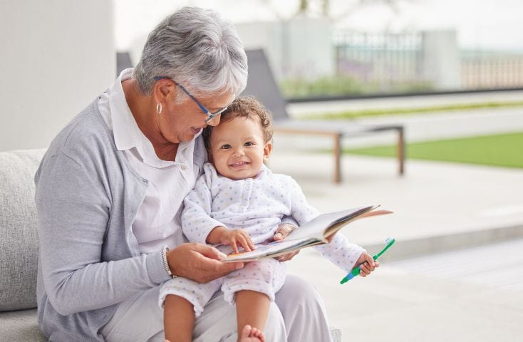 Nonna che legge un libro in inglese al nipotino piccolo sul divano